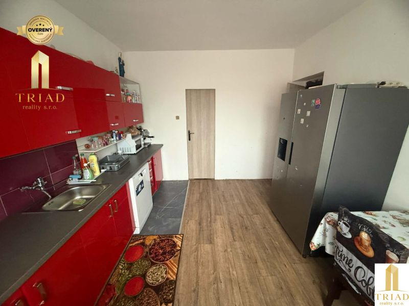 A kitchen in a family house with red cabinets and a wooden decor floor.