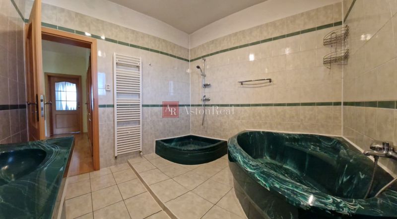 A bathroom in a family house with ceramic tiles and dark green sanitary ware.