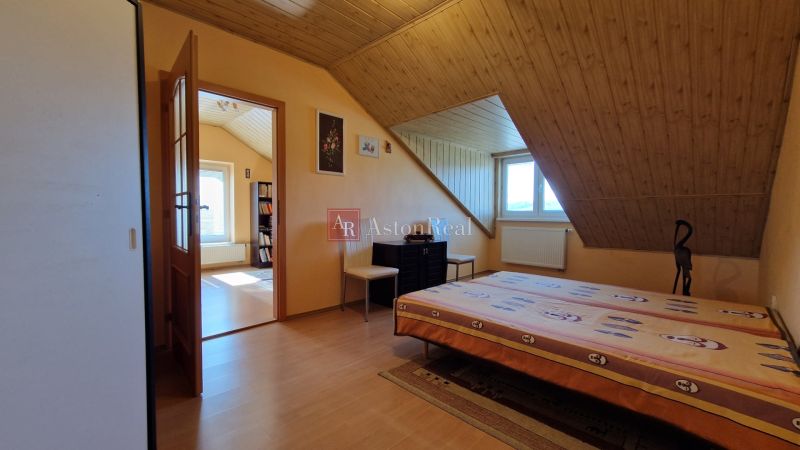 Attic room with a bed, chairs, and a wooden decor floor in a family house.