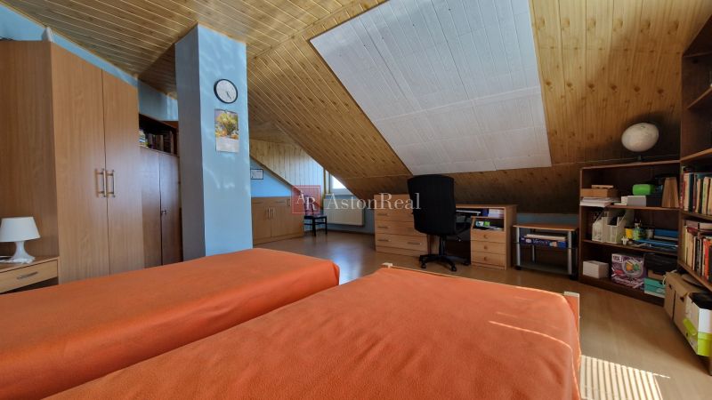 A room in a family house with orange beds, a slanted ceiling, and wooden furniture.