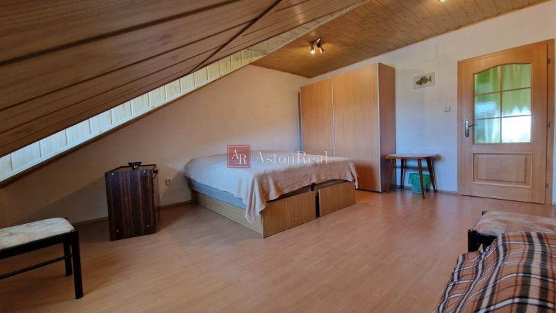 Attic bedroom in a family house with a wooden decor floor and simple furnishings.