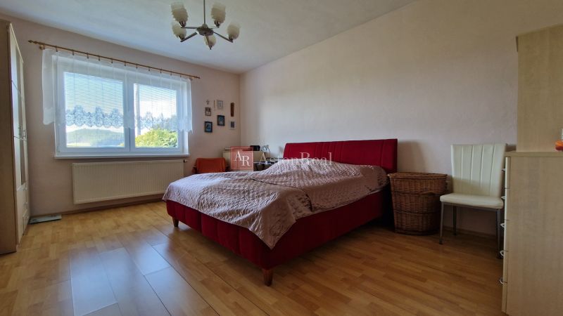 A bedroom in a family house with a double bed and a wooden decor floor.