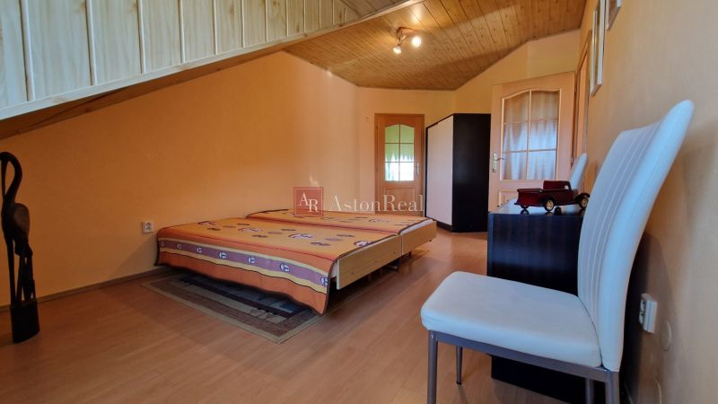 A bedroom in a family house with wooden decor on the ceiling and floor.