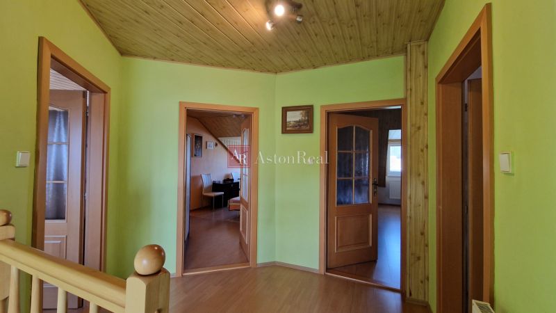 A hallway in a family house with a wooden decor floor, light green walls, and doors.