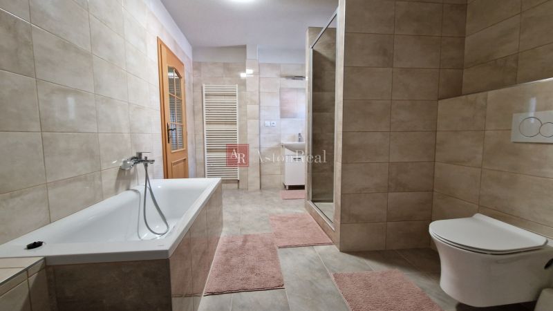 A bathroom in a family house with a bathtub, shower, and ceramic tiles.