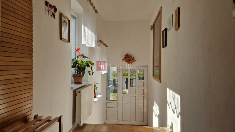 A narrow hallway in a family house with tiles, a plant, and decorative items on the walls.