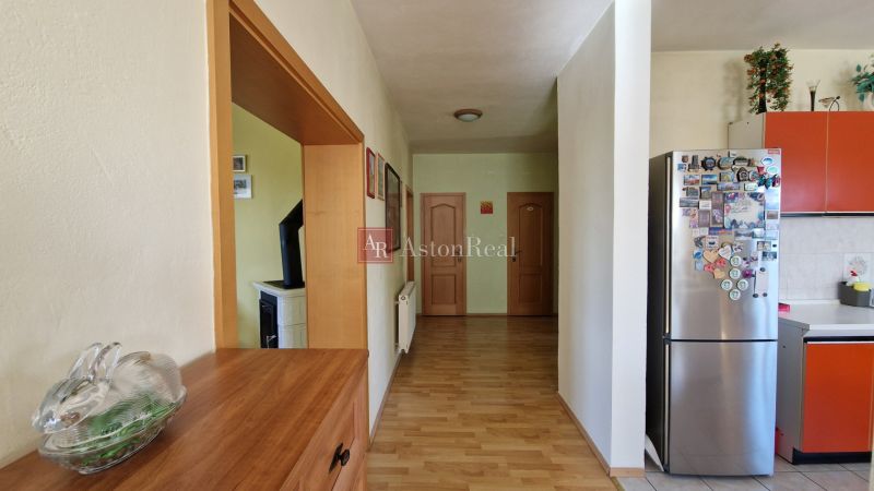 A hallway of a family house with a wooden decor floor, a refrigerator, and decorations.