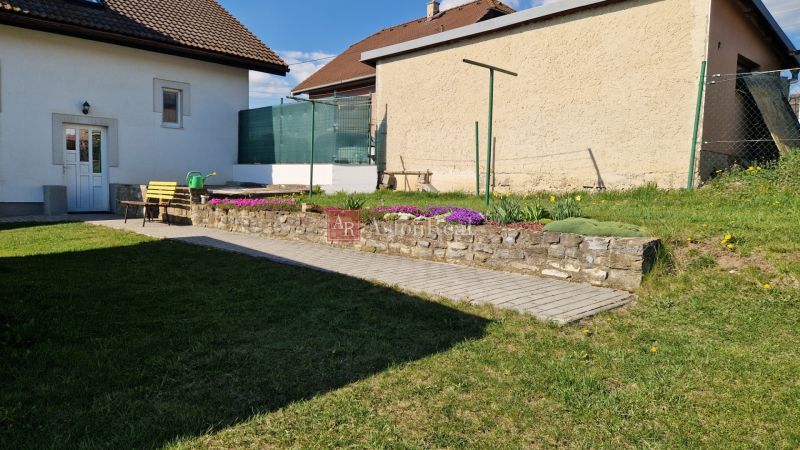 The garden of a family house in Spišský Štvrtok with a bench and flower beds.