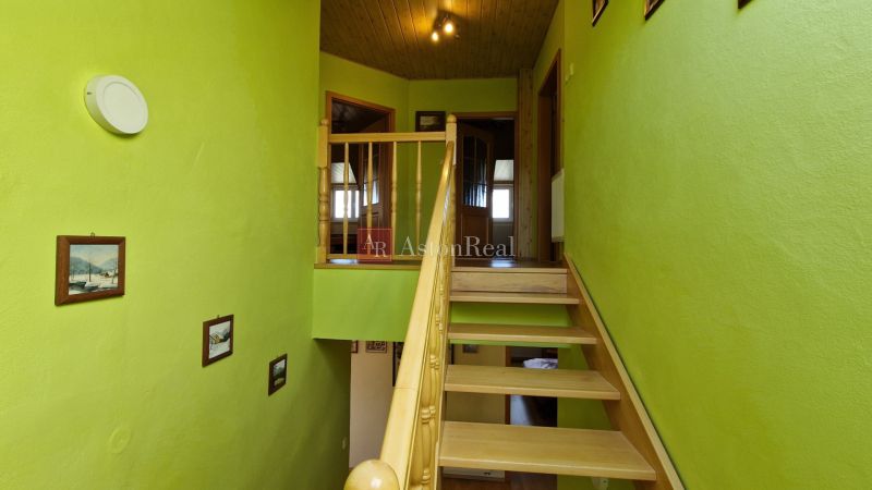Green staircase in a family house with wooden railing and decorative paintings.