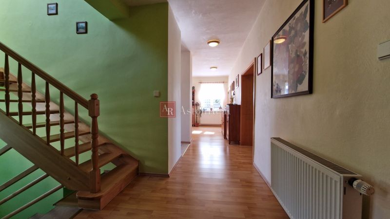 Hallway in a family house with a wooden decor floor, staircase, and decorations.