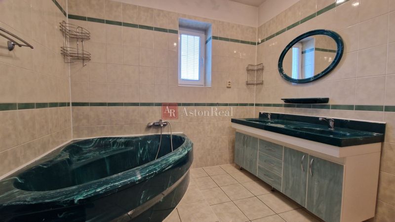 A bathroom in a family house with dark marble sinks and a bathtub.