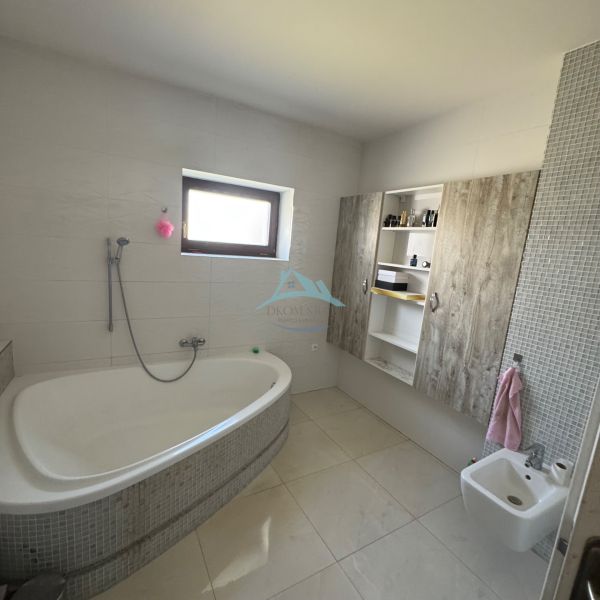 A bathroom in a family house with a bathtub, bidet, and cabinets with a wooden decor.