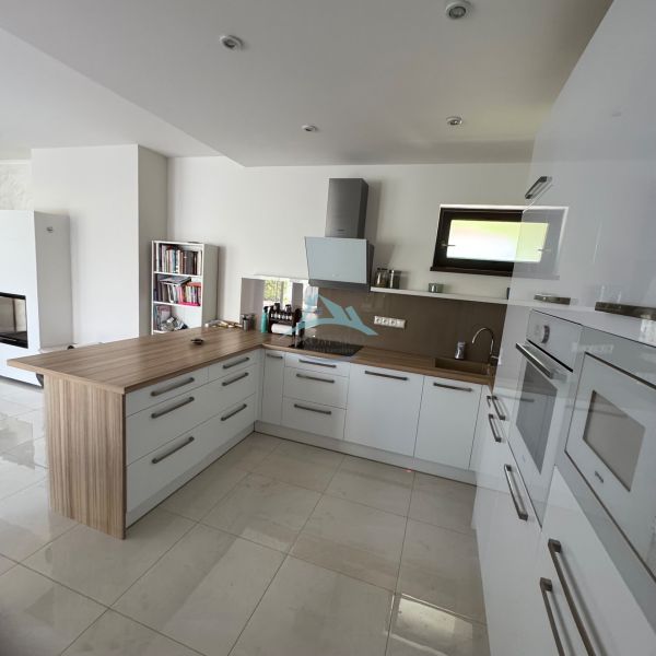 A kitchen in a family house with white cabinets and a wooden decor floor.