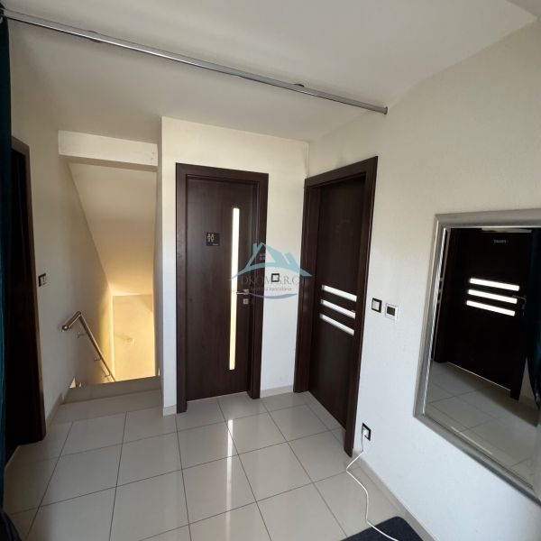 A hallway in a family house with white walls, three dark doors, and a mirror.