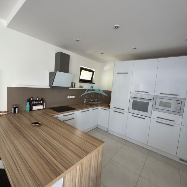 A kitchen in a family house with glossy cabinets and a wooden decor floor.