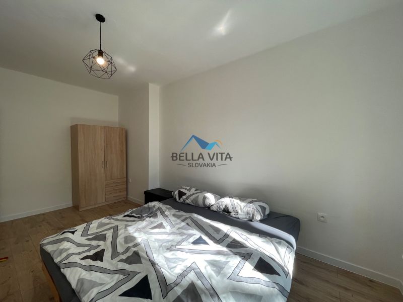 Bedroom in a 2-room apartment with a bed, wardrobe, and floor with wooden decor.