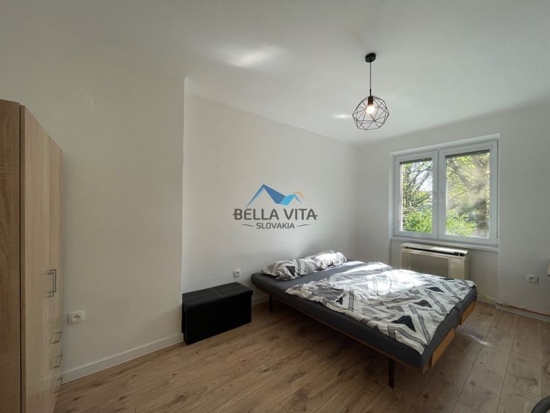A bedroom with a bed and a wooden decor floor in a two-room apartment.