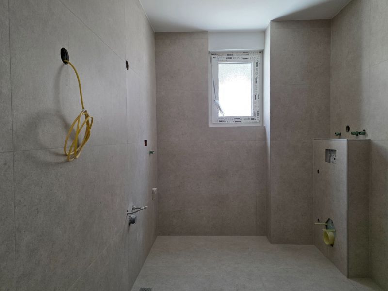 A bathroom in a 3-room apartment with tiles and a window on the wall.