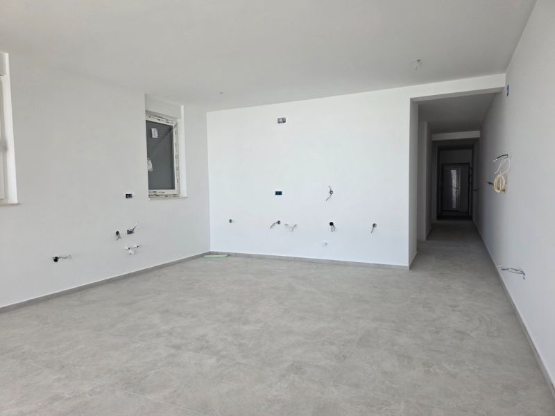An empty interior of a 3-room apartment with white walls and light flooring.