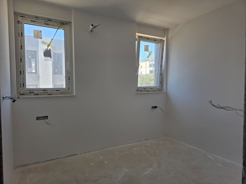 A white interior with two windows in a 3-room apartment, with a wooden decor floor.