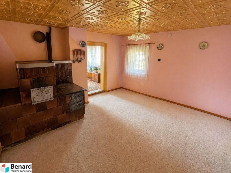 A room in a family house with a tiled stove, light pink walls, decorated ceiling.