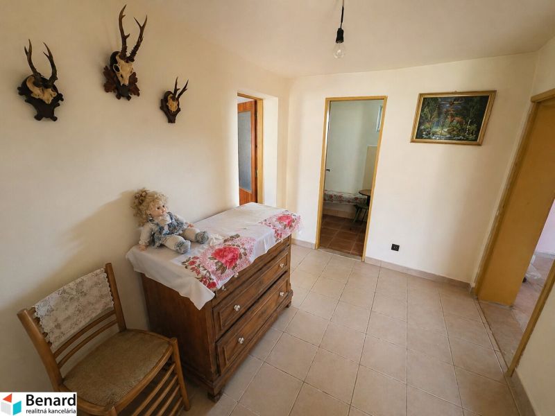 A hallway of a family house with decorations, wooden furniture, and ceramic flooring.
