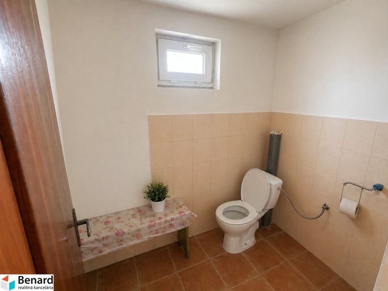 Bathroom with toilet and decorated bench in a family house.
