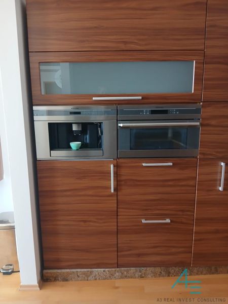 A kitchen unit with a wood decor and built-in appliances in a 2-room apartment.