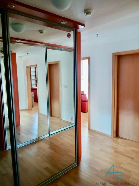 A hallway with a wooden decor floor and a mirrored wardrobe in a 2-room apartment.