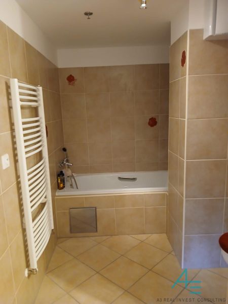 Bathroom in a 2-room apartment with a bathtub and tiled finish, light tones.