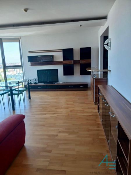 Living room in a two-room apartment with a wood-patterned floor and a large window.