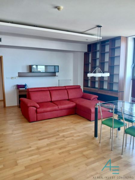 A red sofa set and a glass table in a 2-room apartment with a wooden decor floor.