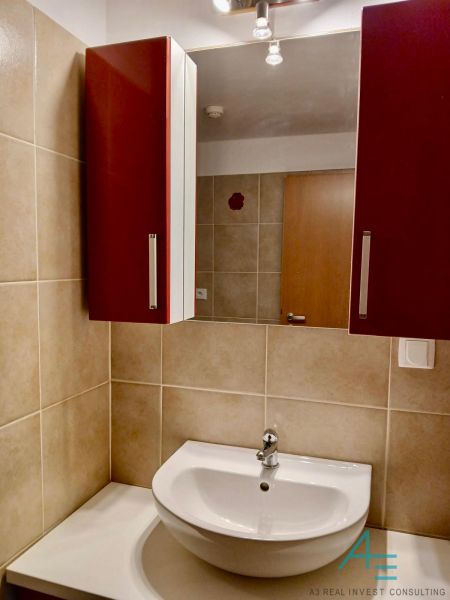 Bathroom in a 2-room apartment with a sink, cabinet, and ceramic tiles.