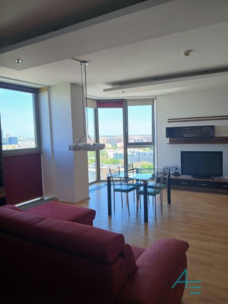 Living room in a two-room apartment with a wood-patterned floor, view through a large window.