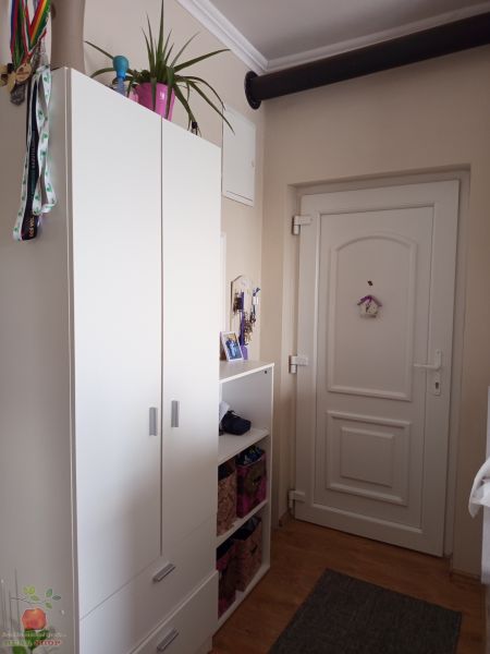 A hallway of a 3-room apartment with a white wardrobe and a wooden decor floor.