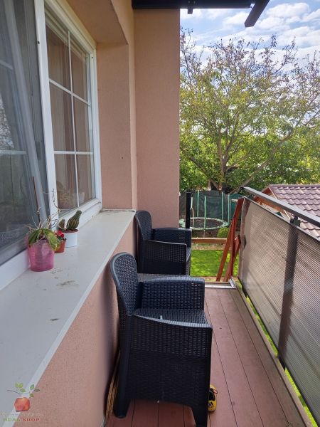 A balcony with plastic chairs and a view of greenery in a 3-room apartment.