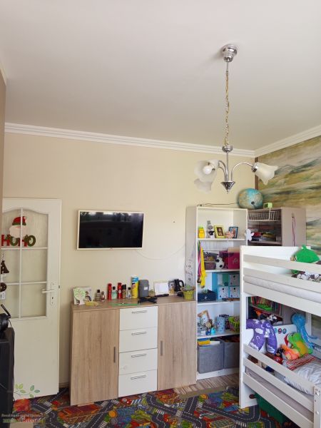 A children's room in a three-room apartment with a bunk bed and a colorful carpet.