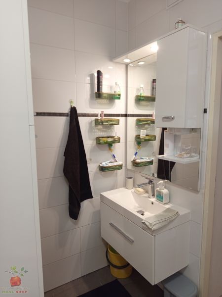 A bathroom with a wall-mounted sink and storage space in a 3-room apartment.