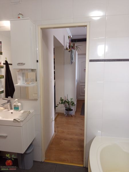 A bathroom in a 3-room apartment with a wooden decor floor and white tiles.