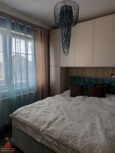 Bedroom in a 3-room apartment with a fluffy bed, curtains, and a decorative chandelier.