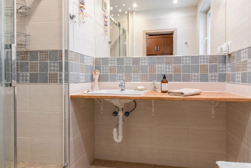 A bathroom in a 3-room apartment with a sink and decorative tiles on the wall.