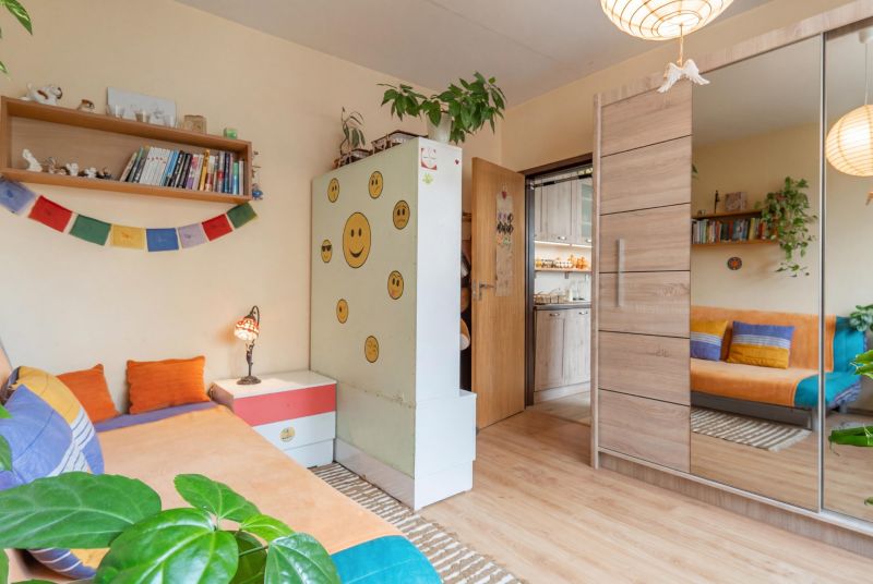 Children's room with a mirrored wardrobe, cheerful decorations, and a wooden-patterned floor.