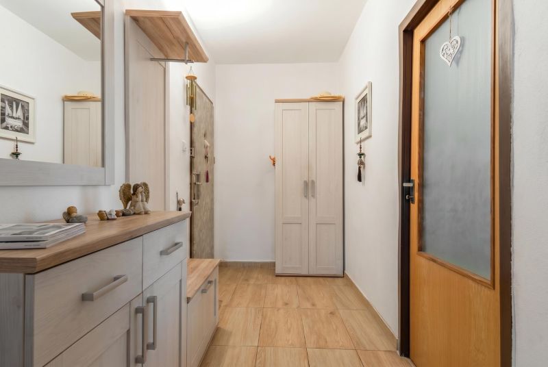 A hallway in a 3-room apartment with a floor featuring a wooden decor and a light-colored wardrobe.