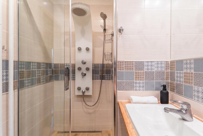 Shower enclosure with a massage jet, modern tiles, and a sink in a 3-room apartment.