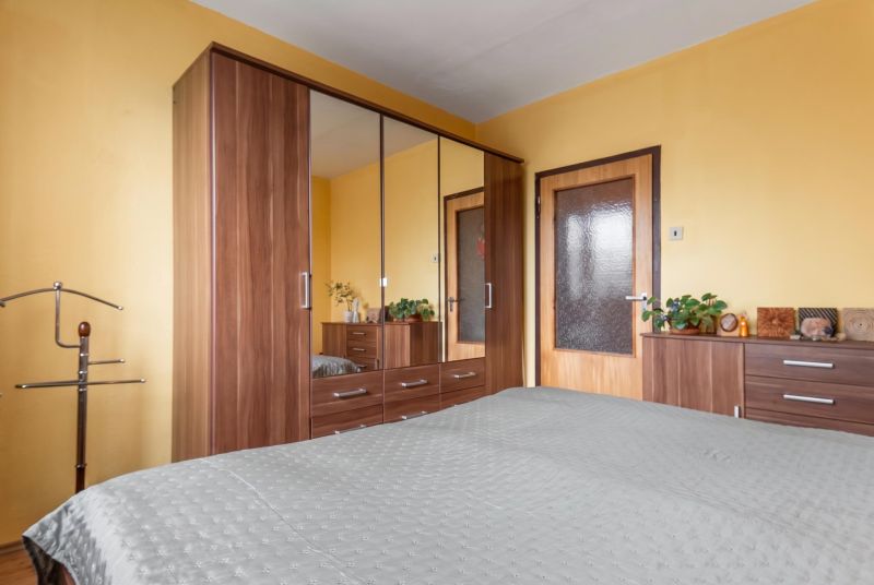 A bedroom in a 3-room apartment with a large wardrobe and wooden decor furniture.
