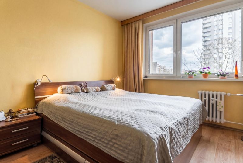 Bedroom in a 3-room apartment with a bed and a wooden decor floor.