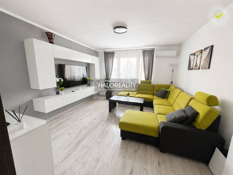 Living room in a three-room apartment with a wooden decor floor and a green sofa.