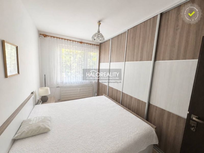 A bedroom in a 3-room apartment with a large wardrobe and a bed, sheer curtains on the window.