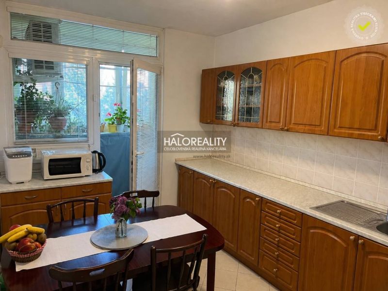 A kitchen in a 3-room apartment with wooden cabinets and access to a balcony.