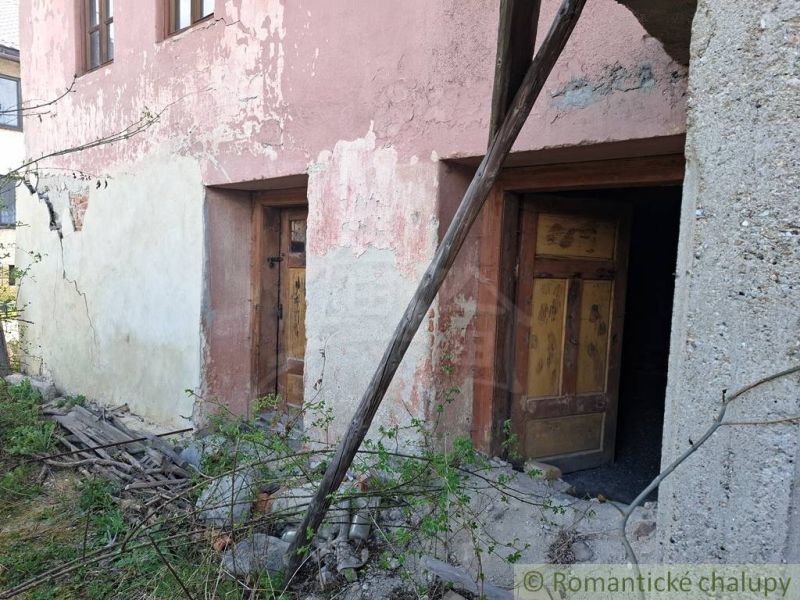 An older building with a neglected facade and wooden doors in Heľpa, unusual properties.